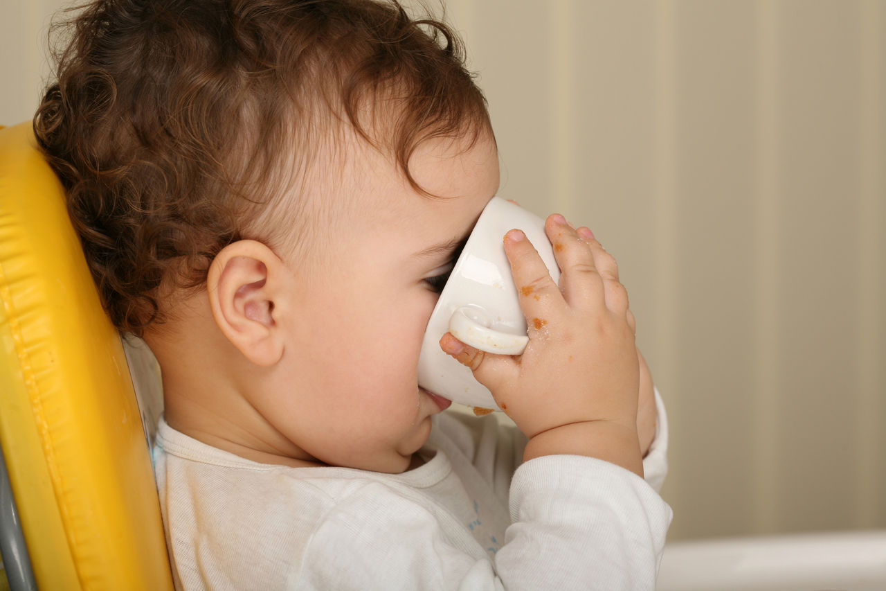 Kleinkind trinkt Milch aus einem Glas