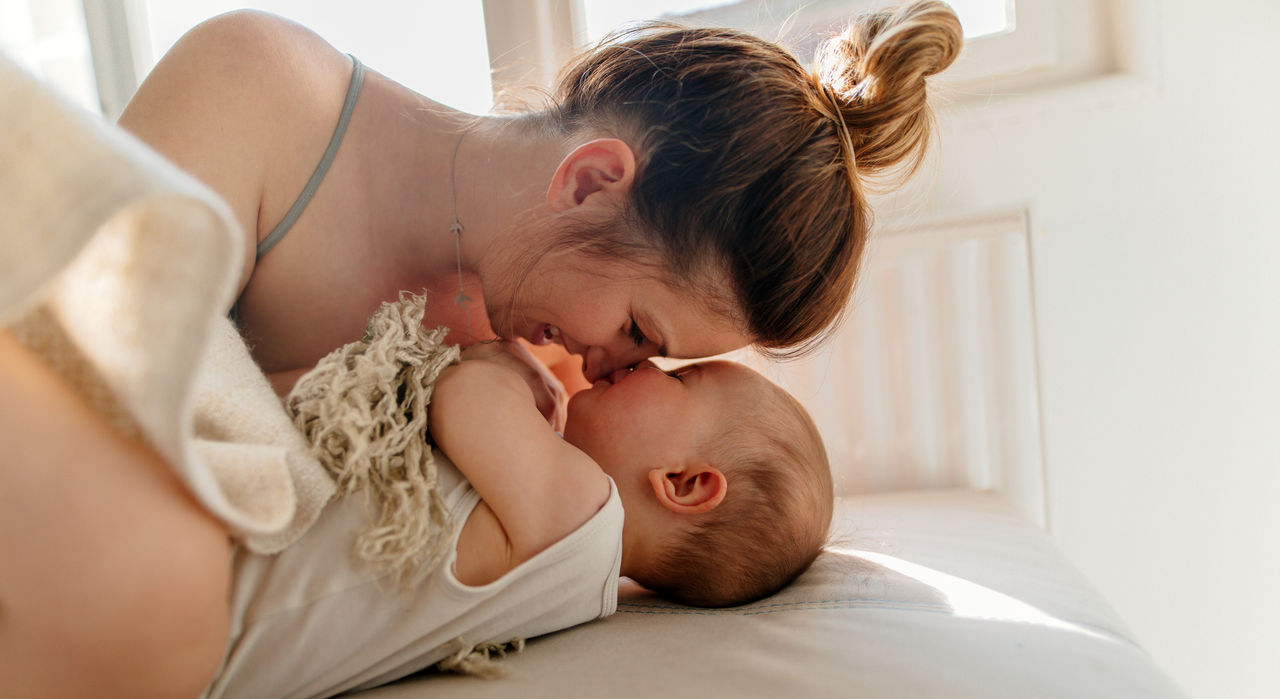 Mother cuddling her baby in bed