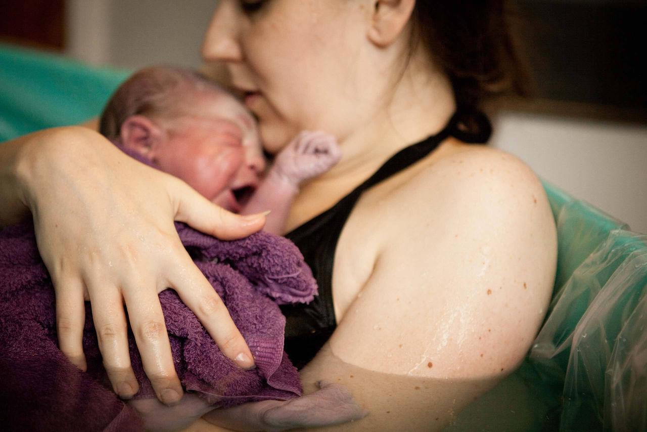 Mutter mit Neugeborenem im Wasserbett: Geburtsposition