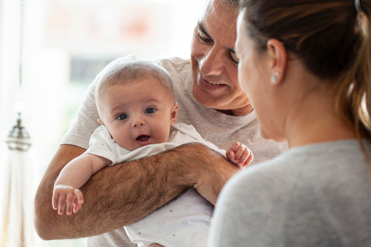 Eltern halten ihr Baby und lachen